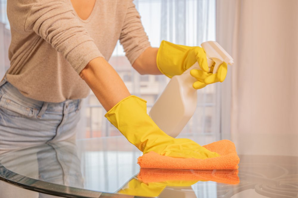 Woman,in,yellow,gloves,cleaning,glass,table.,spraying,and,wiping